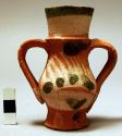 Very small double handled pottery vase- buff colored w/ green & white decoration