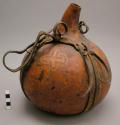 Gourd container, incised decoration, skin carrying strap, approximately 10"