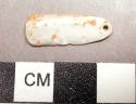 Piece of carved shell with perforation. 2.1 x .7 cm.