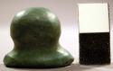 Ground nephrite labret. Head is oval and concave. Base of shaft is grooved.