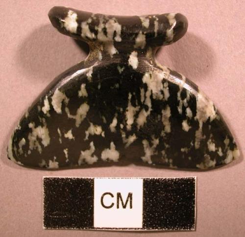 Syenite labret. Head is oval, flared, and concave. Shaft is flared, tapered.