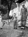 Man with two boys and dog in front of wayside temple