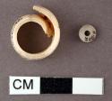 Shell bead - darkened from cremation fire - .5 x .1 cm.