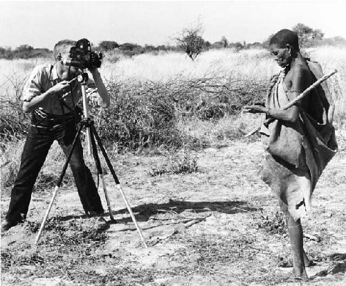 /Twikwe standing with digging stick, being filmed by John Marshall