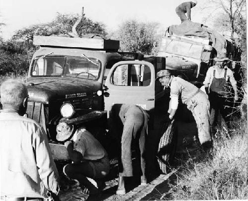 Group of men working on stuck expedition trucks