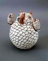 Polychrome-on-white owl with smaller owls on wings and mouse in beak