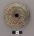 Ground stone; perforated; disk in form; 1 large & several small losses at edge