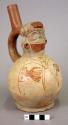 Ceramic bottle, stirrup spout, molded head, red on cream hands painted on