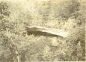 Rock shelter in wooded area, man sitting in shelter