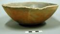 Outcurved bowl; slightly concave base, chipped rim, otherwise intact, small fire