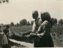 Man and woman holding baskets, children at left in In bean field at Lake Co.