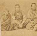 Studio shot of three young people seated with legs crossed