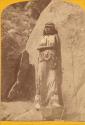 Ku-ra-tu, woman standing alongside rocks.