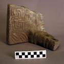 Fragment of carved stone metate, with one support.  Curvilinear motifs.  6 1/4"h