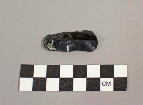 Obsidian blade with small flakes around edges