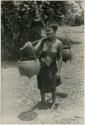 Woman carrying pots suspended on a pole