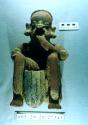 Ceramic seated male Figure eating from a pot held between knees