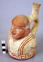 Ceramic bottle, stirrup spout, human effigy, molded head & torso, red on white