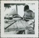 Photograph album, Yaruro fieldwork, p. 8, photo 1, man working at construction table, possibly making a belt