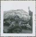 Photograph album, Yaruro fieldwork, p. 52, photo 2, young girl outside thatched building