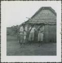 Photograph album, Yaruro fieldwork, p. 55, photo 1, three men outside thatched building
