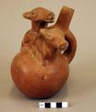 Ceramic stirrup spout bottle, mating animal effigies, molded, orange decoration