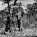 "Short /Qui" carrying his hunting equipment on his back, being filmed by John Marshall, using a pulley to take a close-up