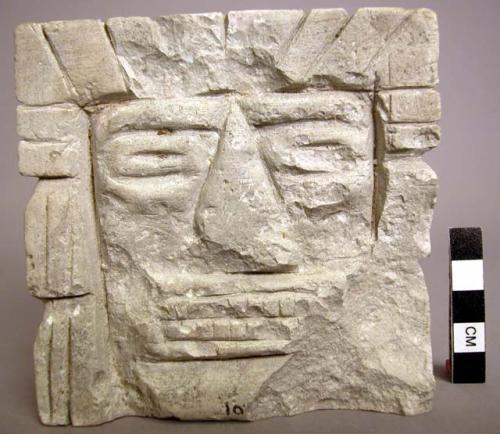 Ground stone sculpture, carved human facial features & headdress, chipped
