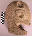 Stone head (thin) in profile view with 2 large circular designs carved on either