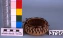 Small round coiled basket, brown woven design and one row of feathers around rim