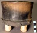 Tan to black flat-bottomed straight-sided pottery tripod bowl