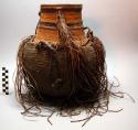 Gourd covered with close cord-netting and with basketry neck; worked +