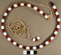 Necklace, red and white glass beads on twisted fiber cord.