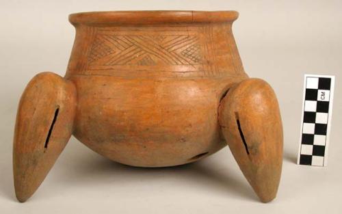 Orange-brown tripod pot - 2 legs, third missing, incised geometric design.