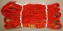 Woman's hair ornament.  2 ply red woolen strands, overcast at intervals with bla
