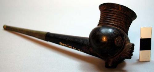 Metal and wood pipe, with an anthropomorphic face on the bowl.  Face has metal