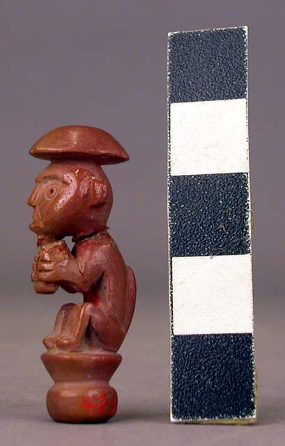 Small seated pottery figurine - monkey with human face; hole in bottom; used as