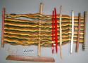 Loom endpiece, carved wood, carved handles, red dyed, still attached to loom