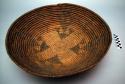 Red coiled flat based basketry bowl. Thick coils with rough stitching