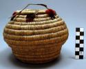 Basket with flat cover - decorated at top with strands of red and black wool; te