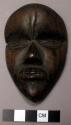 Small wooden mask - property of a man who prays to it for good luck and also sac