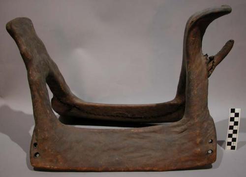 Plains woman's saddle. Wood frame covered w/ rawhide. High cantle and mantle.