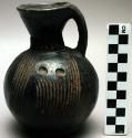 Black jug with handle and incised designs, ht: 14 cm; diam. of rim: 6 cm.  Diam