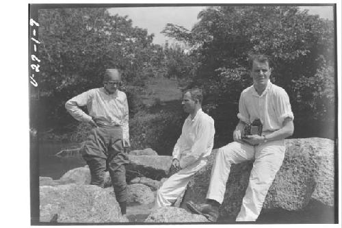 Staff members sitting on rocks next to river