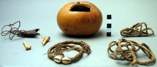 Gourd container with hole cut in side, contains 2 bones, woven strands of straw