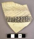 Ceramic rim sherd, black on cream, curved chevron, reticulated band, thin