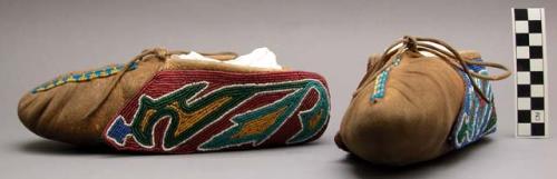 Pair of skin moccasins with cuffs of colorful designs of glass beads.