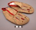 Pair of Plains child's moccasins, probably Ponca. Red cloth trim, embroidery