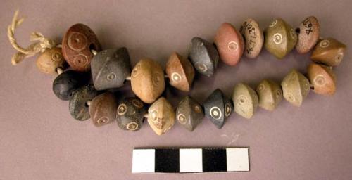 Ground stone beads on string, circular, incised