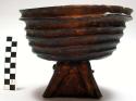Wooden porridge bowl - footed, painted black, sides ribbed, string through base
